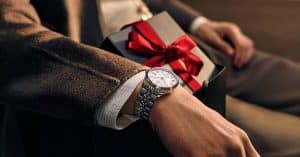 Armbåndsur fra Tissot på en person som holder en gave pakket inn i rødt gavebånd